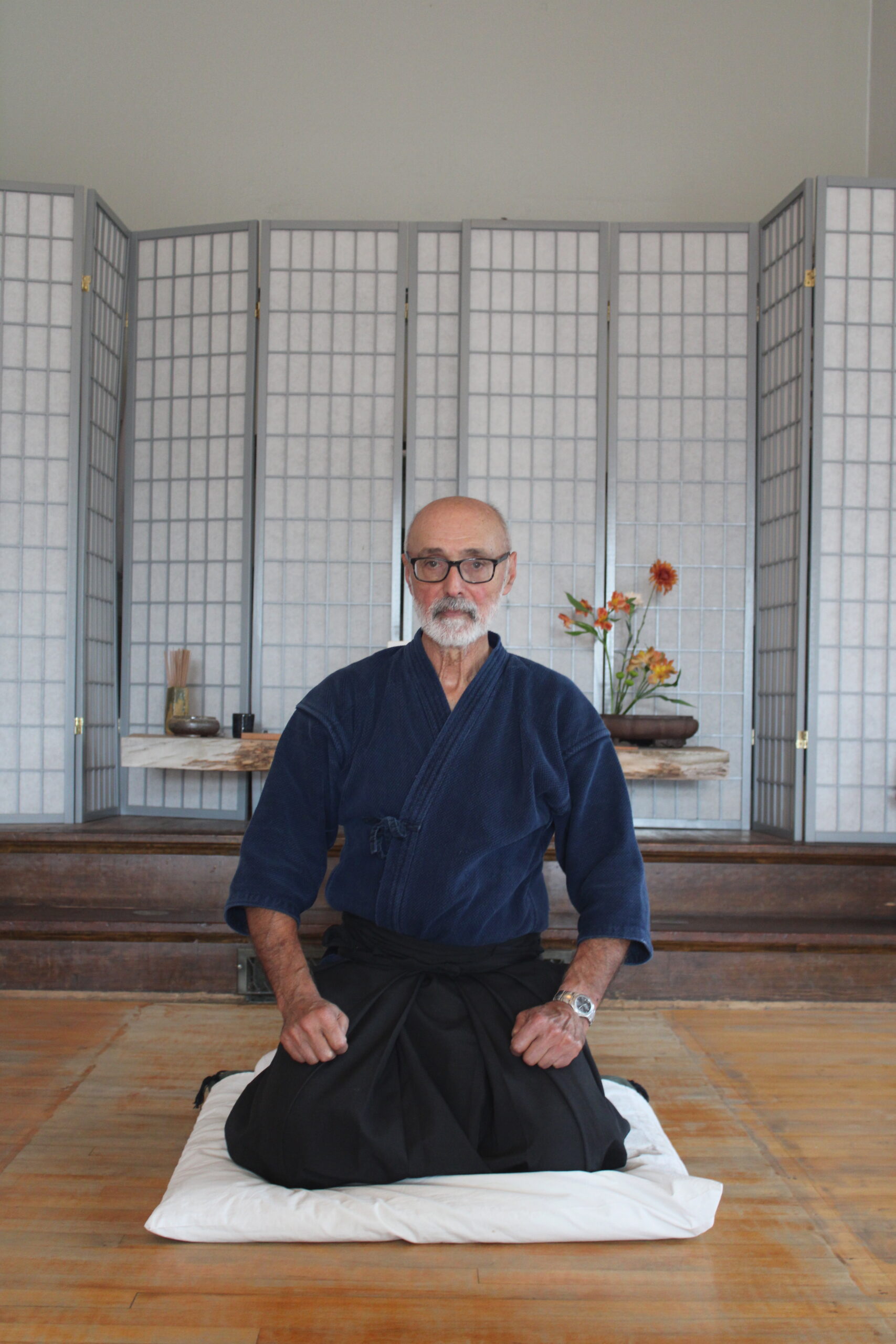 Man sits on knees in meditation space. 