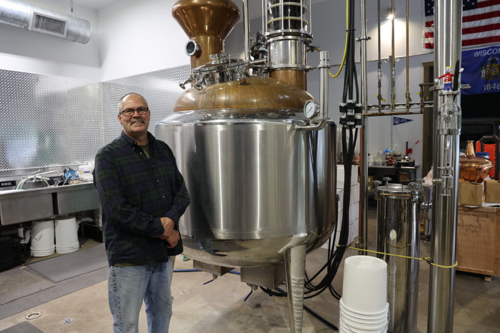 Man standing by metal distillation column.