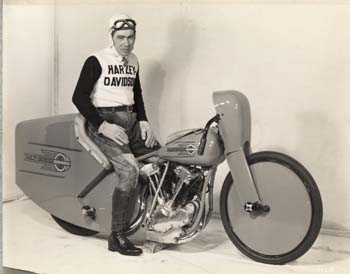 Old photo of man on motorcycle.